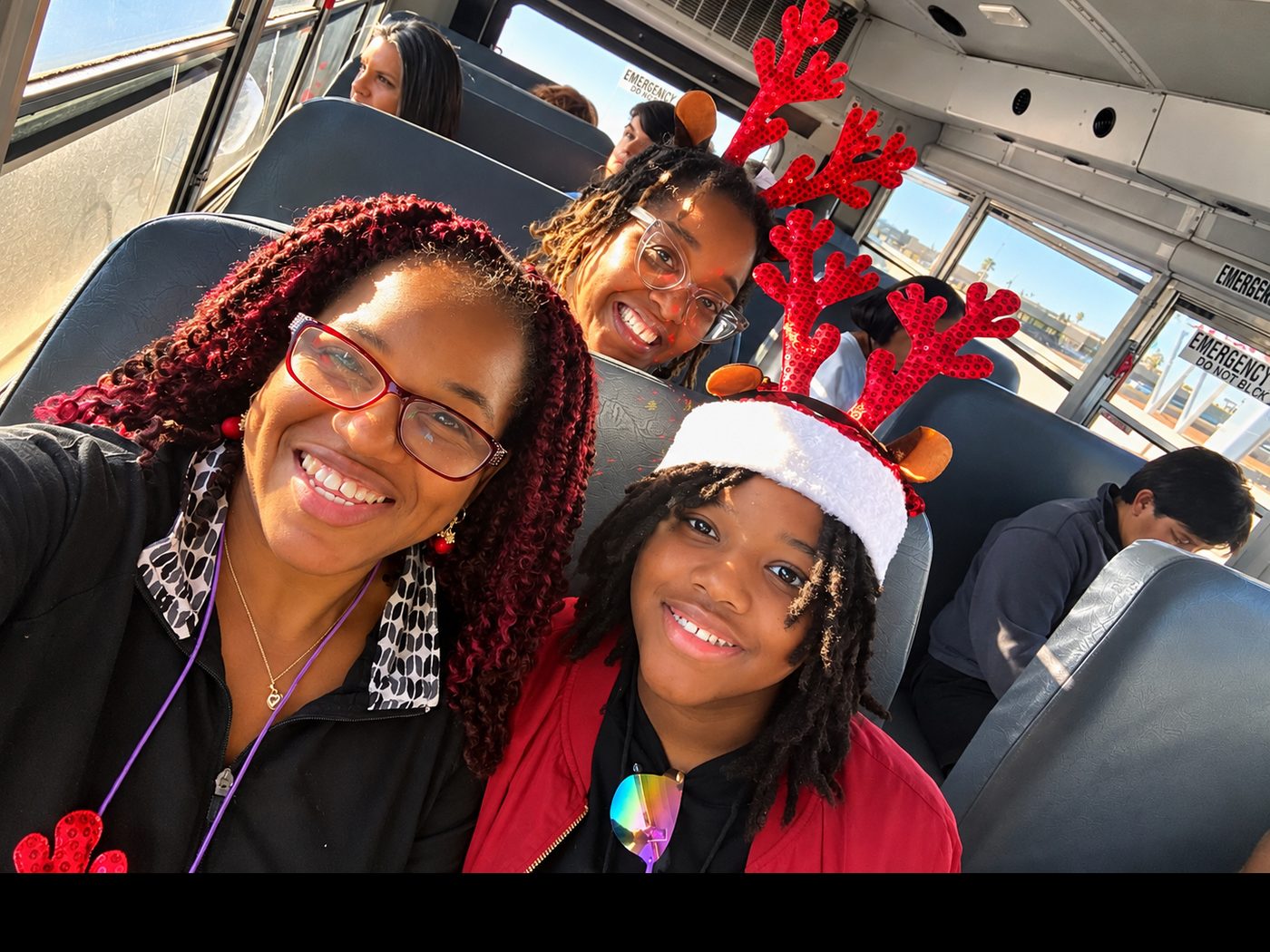 Young people smiling together on a bus, some wearing reindeer antlers